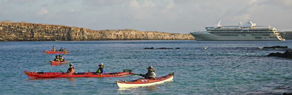 Silversea Cruises Expedition ship in the background of people kayaking infront on the sea - Best Expedition Cruise Lines 2026 Our Top Picks
