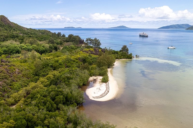 swan hellenic's sh vega sailing close to a lush green island in the seychells.