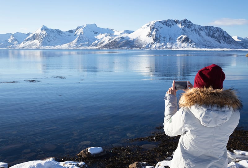 Lofoten Islands girl taking picture of the Norwegian landscape - Northern Lights Cruises 2026 When, Where and How to See the Aurora
