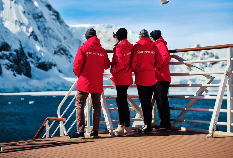 Silversea Cruises Silver Endeavour's deck glacier with snow-covered mountain guests with Silversea Expedition Red Parka Jacket - Silversea Packing & Dress Code Guide