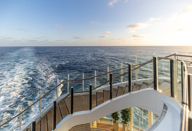 Silversea Cruises with spiral stairs with waves & sunset in the background - How to Choose the Right Cruise Cabin Inside, Balcony or Suite
