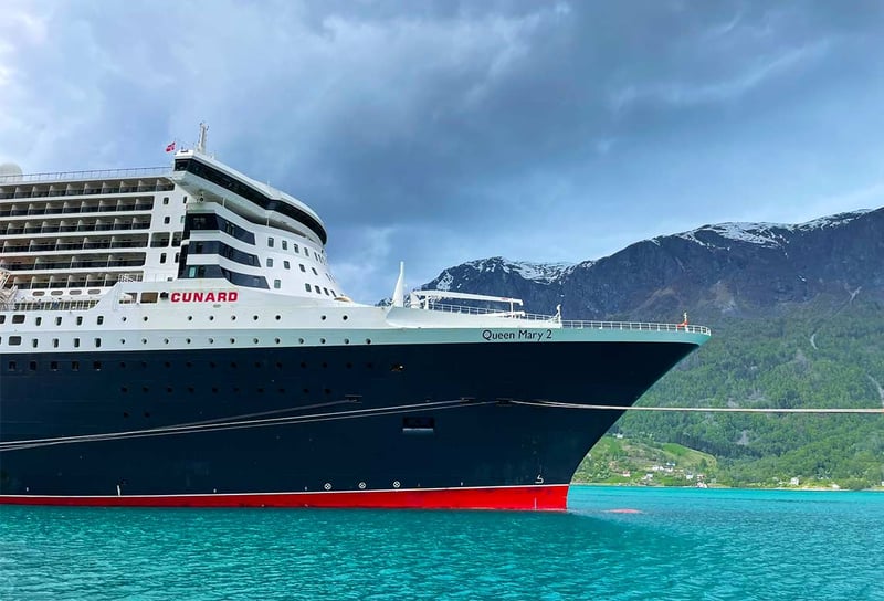 Cunard-Queen-Mary-2-docked-in-Norway-with-Mountain-in-background-Norwegian-Fjords-on-QM2-What-to-Expect