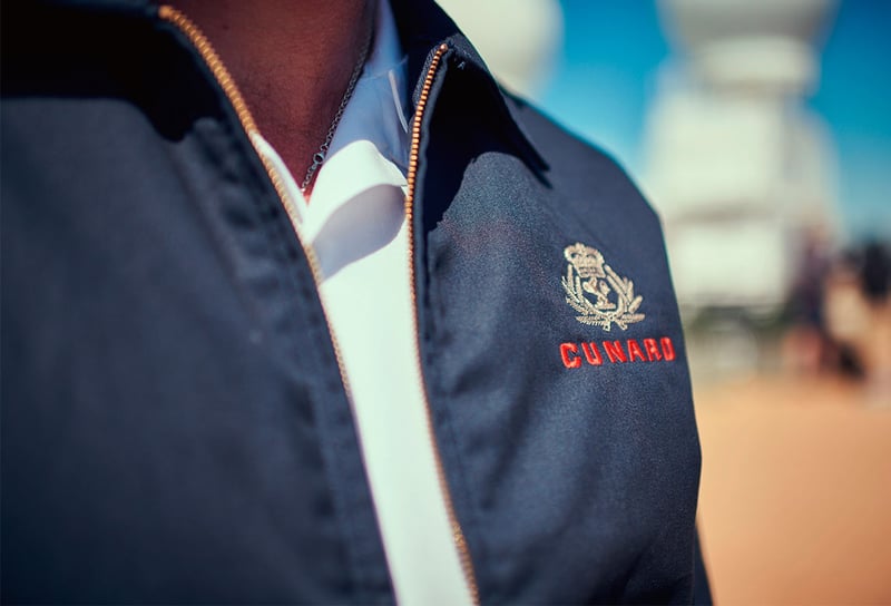 Cunard-Cruises-in-Alaska-Crew-Member-with-Cunard-Uniform-Understanding-auto-gratuities-&-service-charges-across-luxury-lines